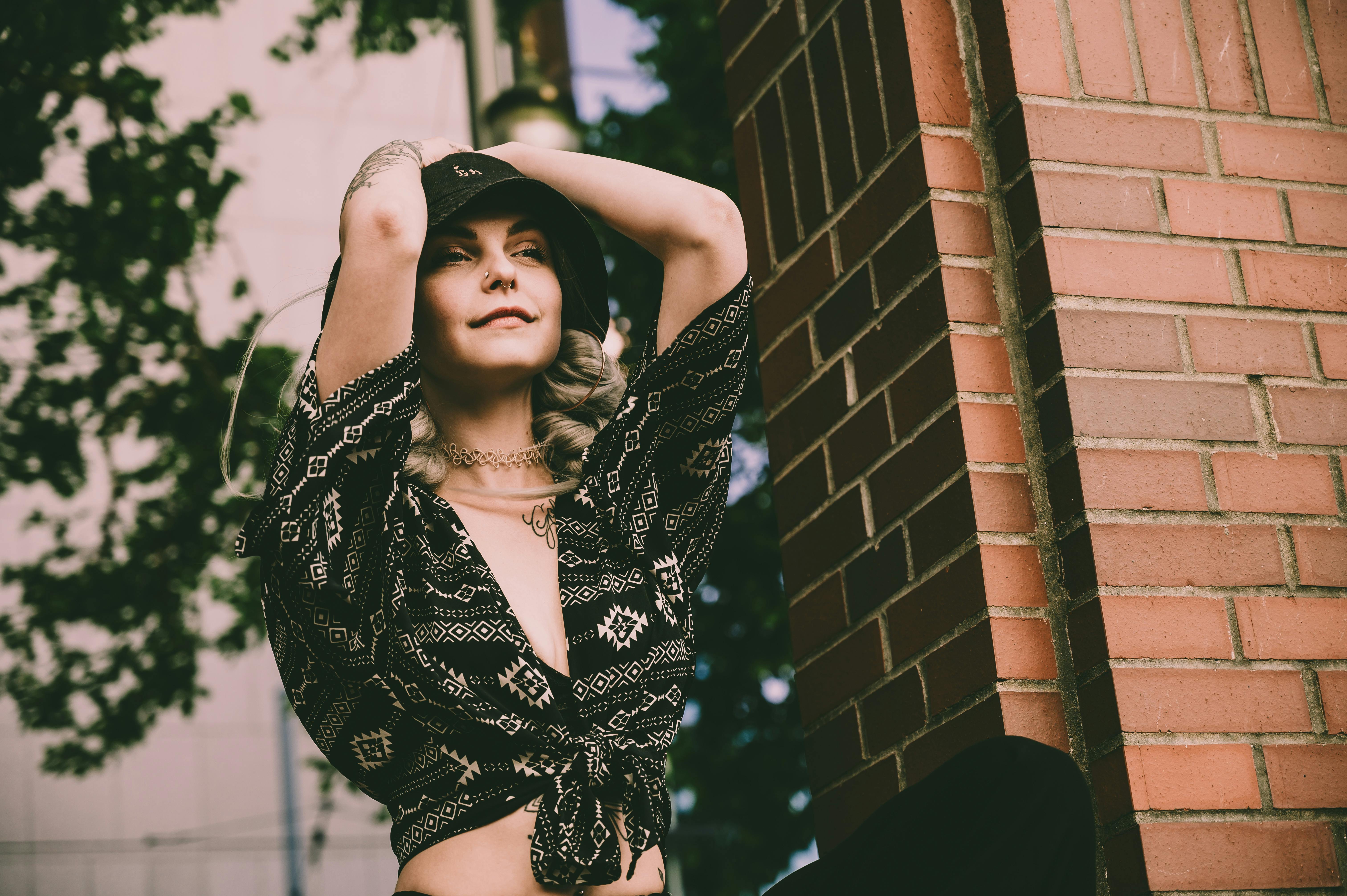 一位时尚女性在户外对着砖墙摆姿势，自信又时髦