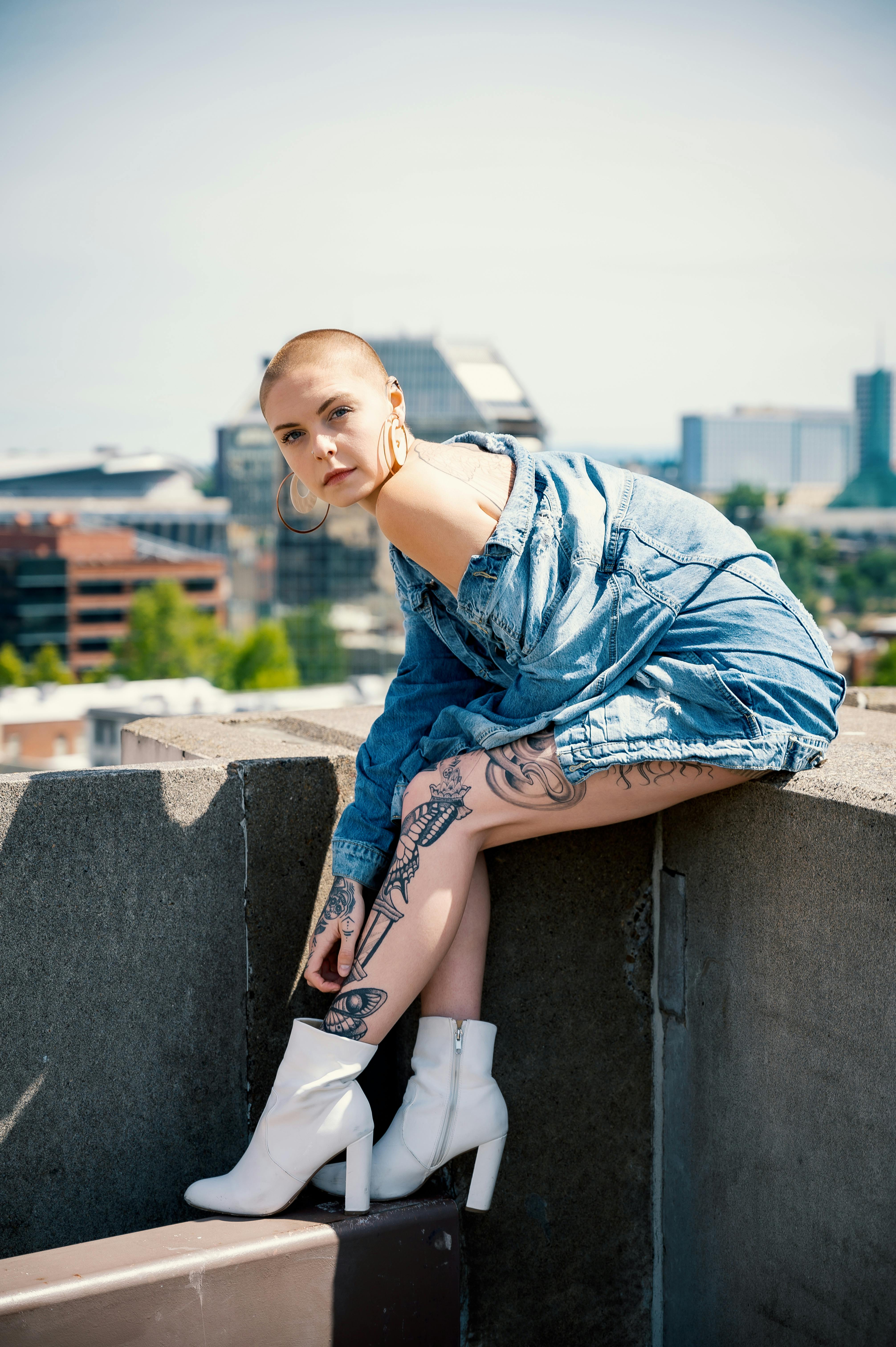 Stylish portrait of a woman in denim with tattoos, set in an urban scene.