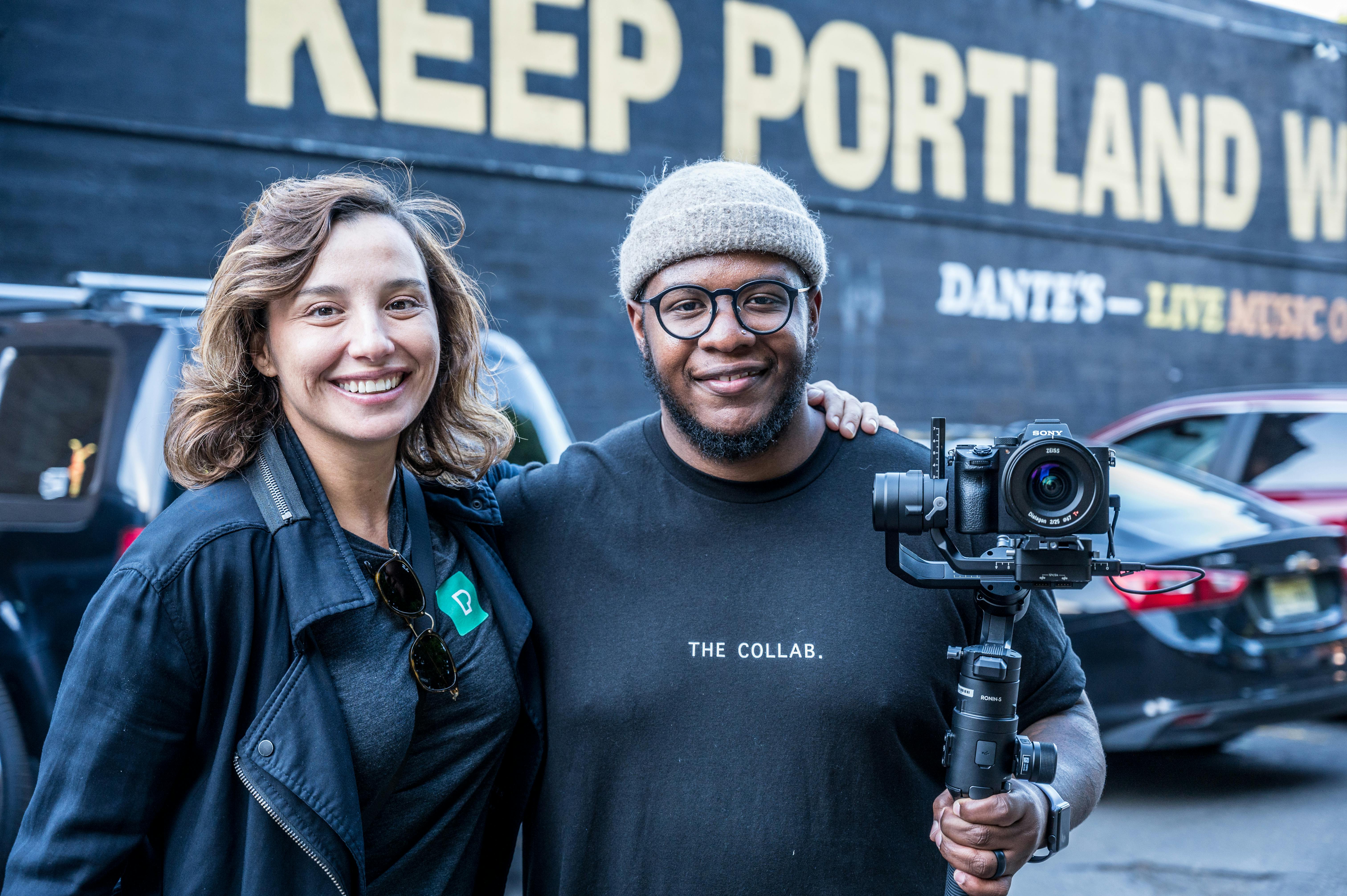 Two photographers pose happily in Portland with camera gear, capturing the city's creative vibe.