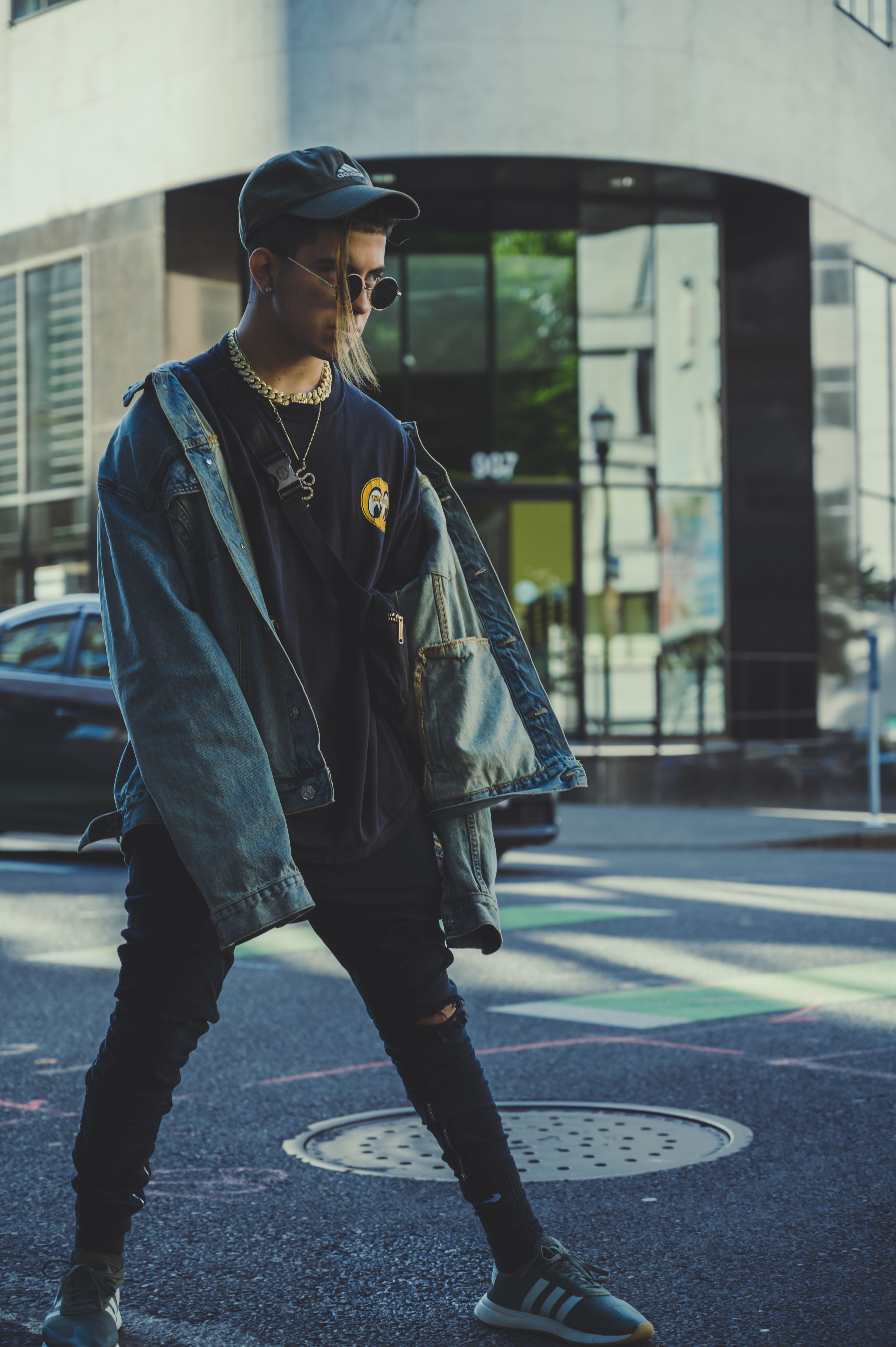Um jovem estiloso em traje urbano casual caminha por uma rua da cidade, exalando vibes de moda moderna.