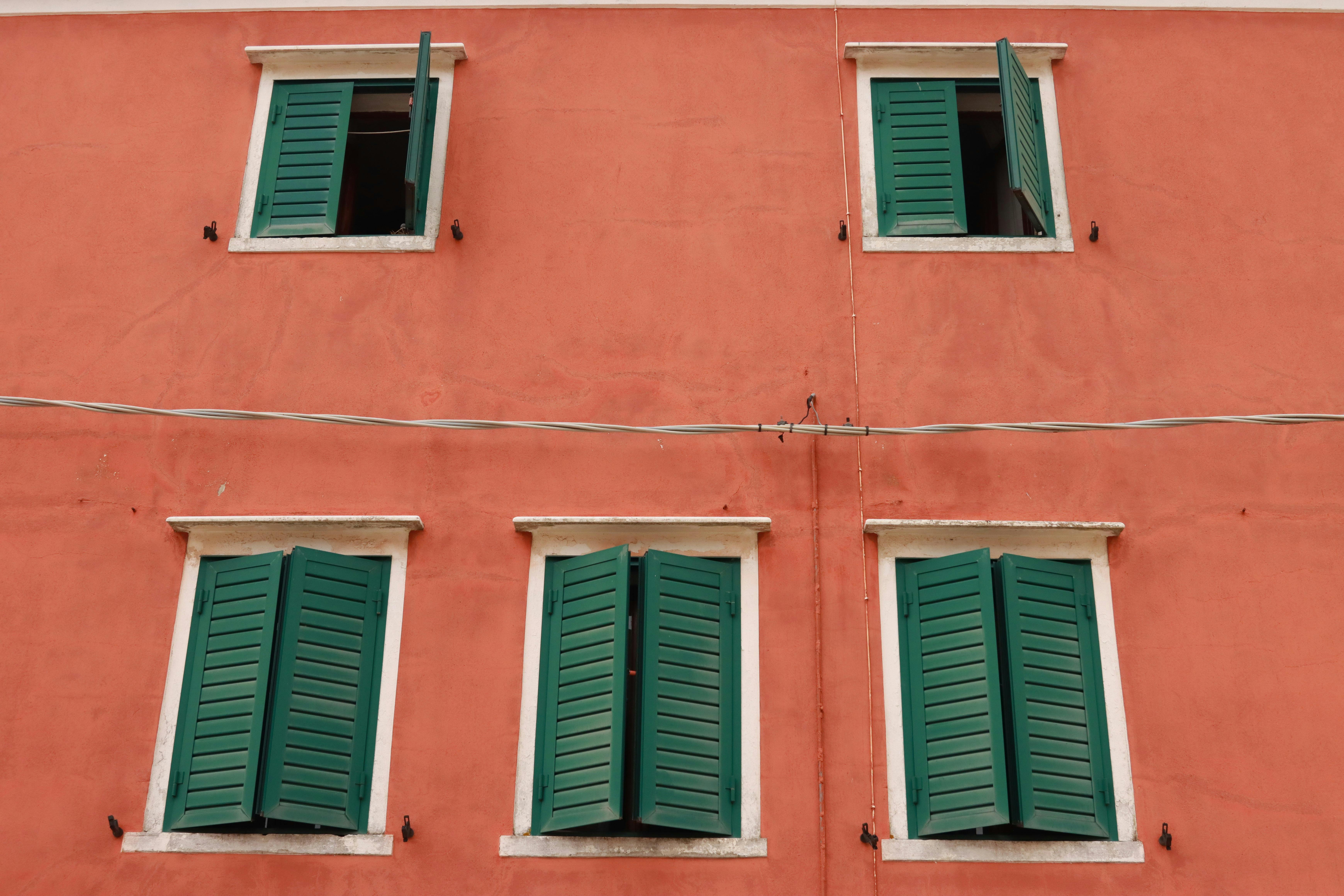 Charming Venetian building facade with green shutters, showcasing classic architecture of Venice, Italy.