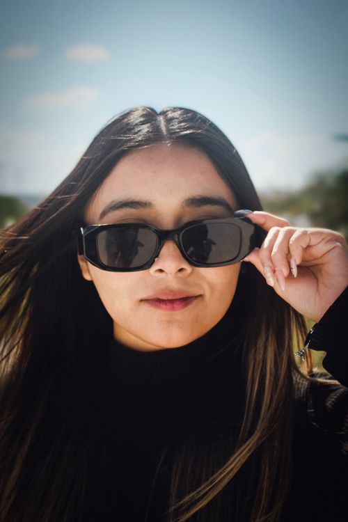 Free Fashionable woman posing outdoors with sunglasses on a sunny day. Stock Photo