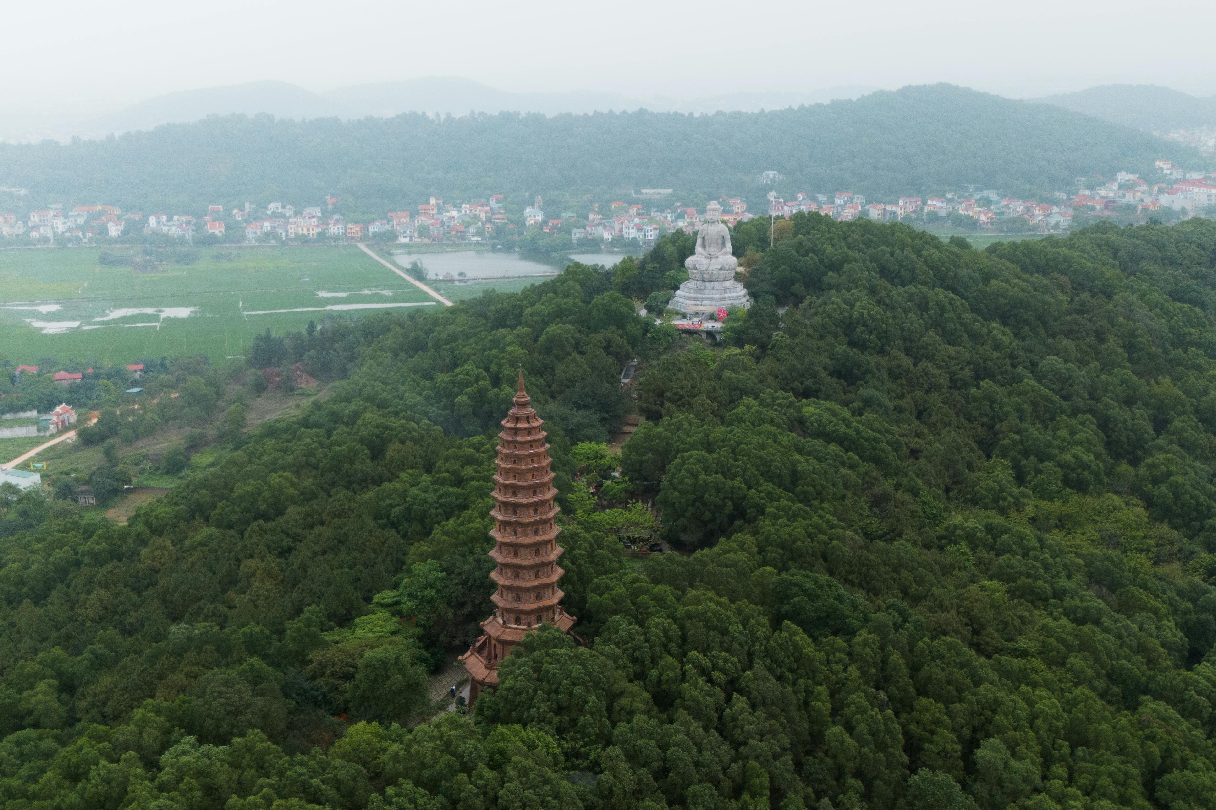 Aerial shot of Phat Tich Pagoda surrounded by lush forests in Bac Ninh, Vietnam.