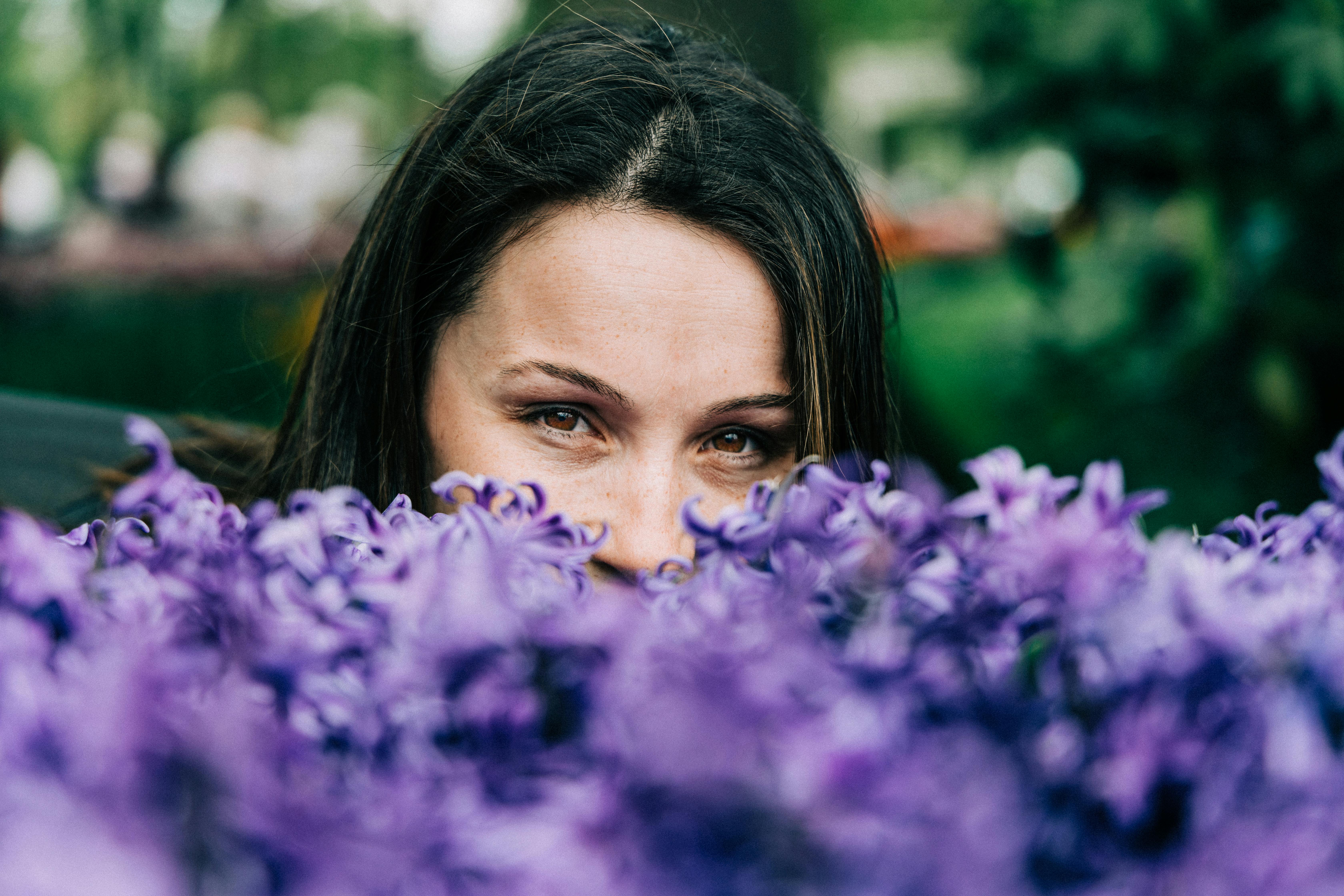 在荷兰的户外，一个女人正透过充满活力的紫色花朵偷看
