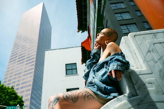 一位身着牛仔夹克的女人，正以高耸的摩天大楼为背景，在户外晒太阳