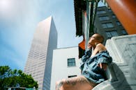 一名纹身女子身着牛仔装，在城市阳光下对着摩天大楼摆姿势