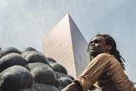 一位时尚男士与城市雕塑，映衬着现代建筑和充满活力的都市生活