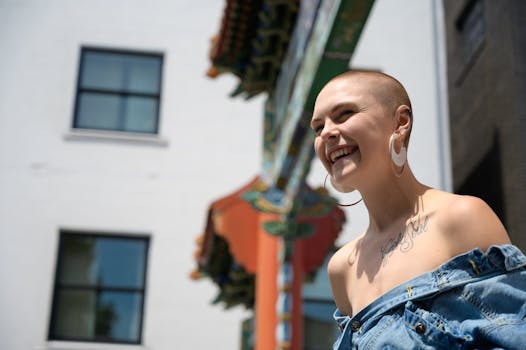 一位时尚女性，身有纹身、戴着耳环，在充满活力的城市背景中灿烂微笑