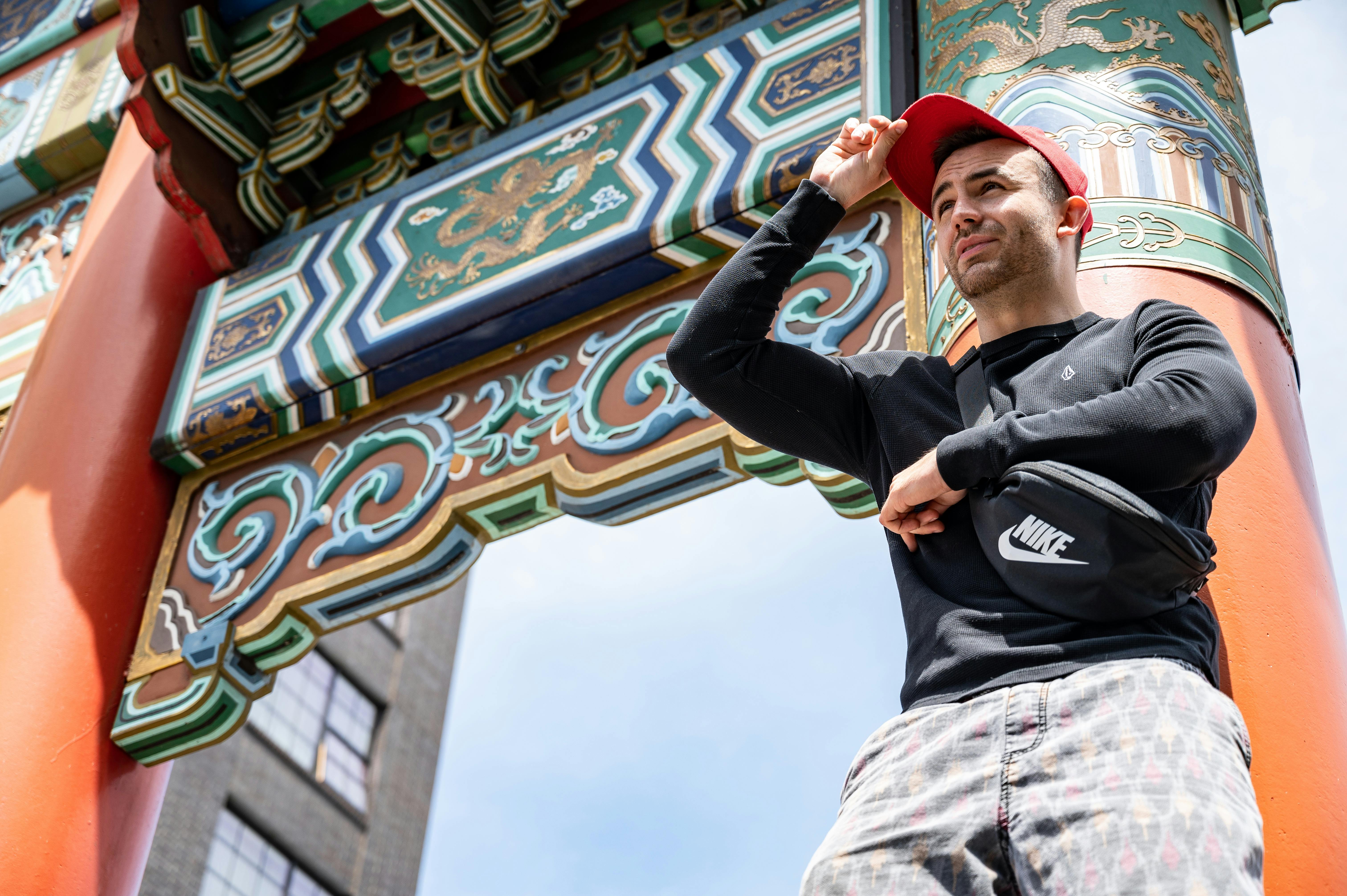 一位戴着帽子的男子在传统的中式大门下摆姿势，色彩鲜艳夺目