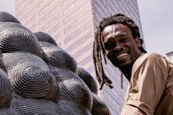 一个开朗的男人留着辫子，在城市景观中摆出雕塑的姿势