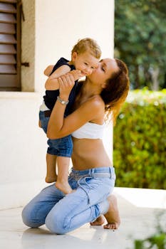 一位慈爱的母亲在阳光灿烂的户外亲吻她的儿子