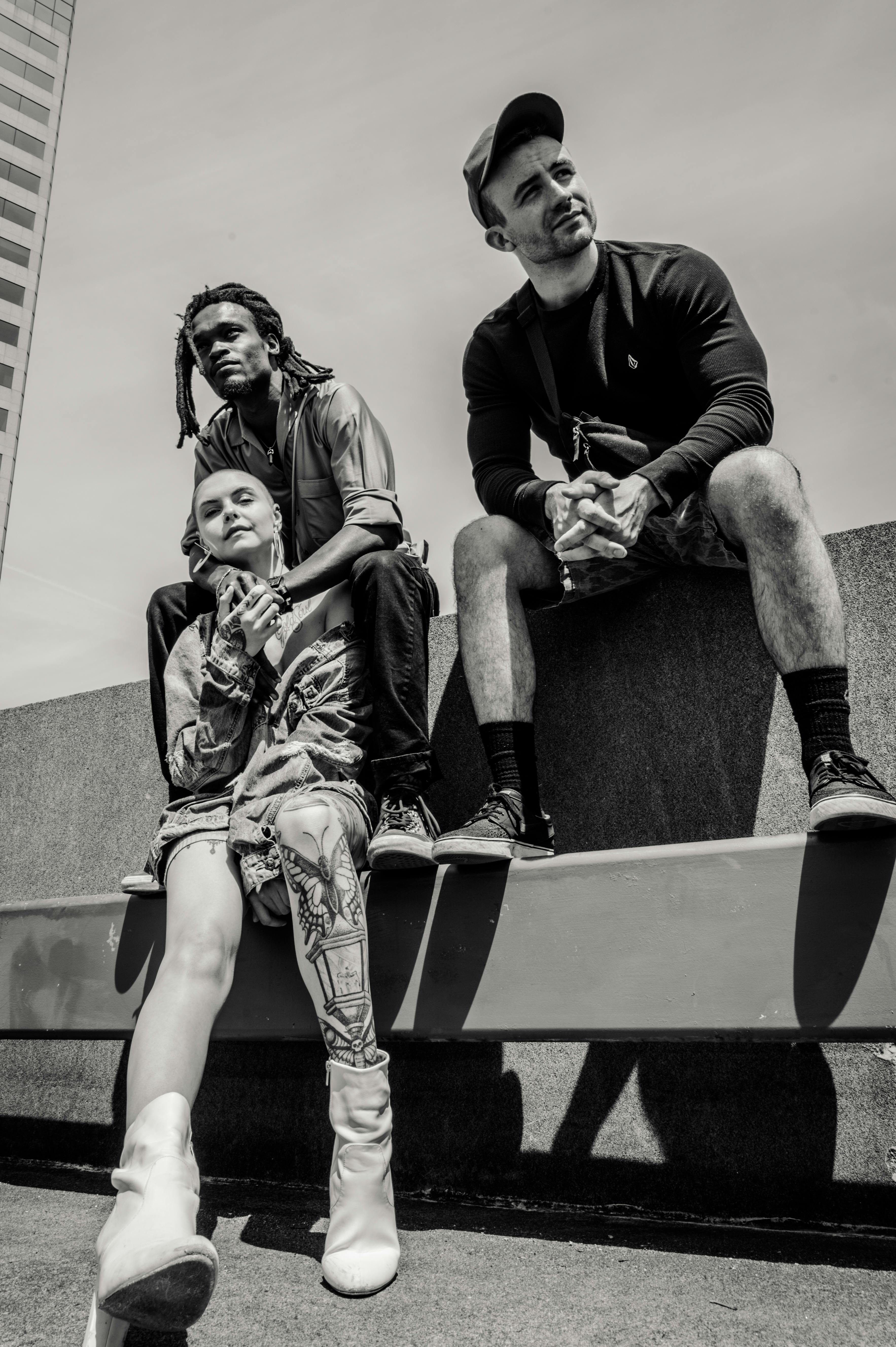 三位成年人在城市时尚的屋顶上摆出不同姿势，捕捉现代友谊的瞬间