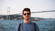 Man Wearing Sunglasses Posing Against a Bridge