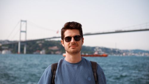 Free A man in sunglasses posing by the Bosphorus Bridge, Istanbul with a serene backdrop. Stock Photo
