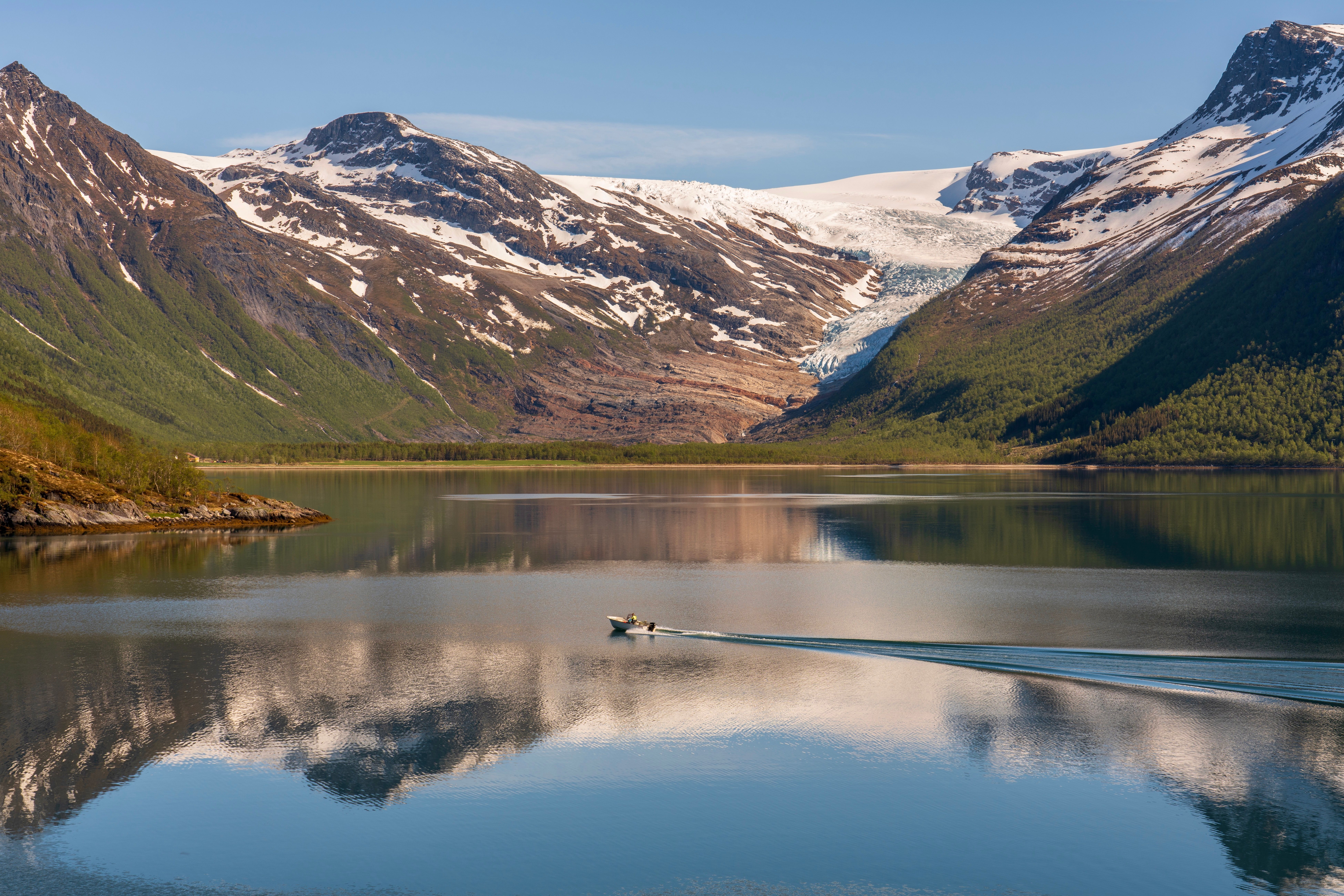 A boat on a Norwegian lake with snow still on the peaks behind