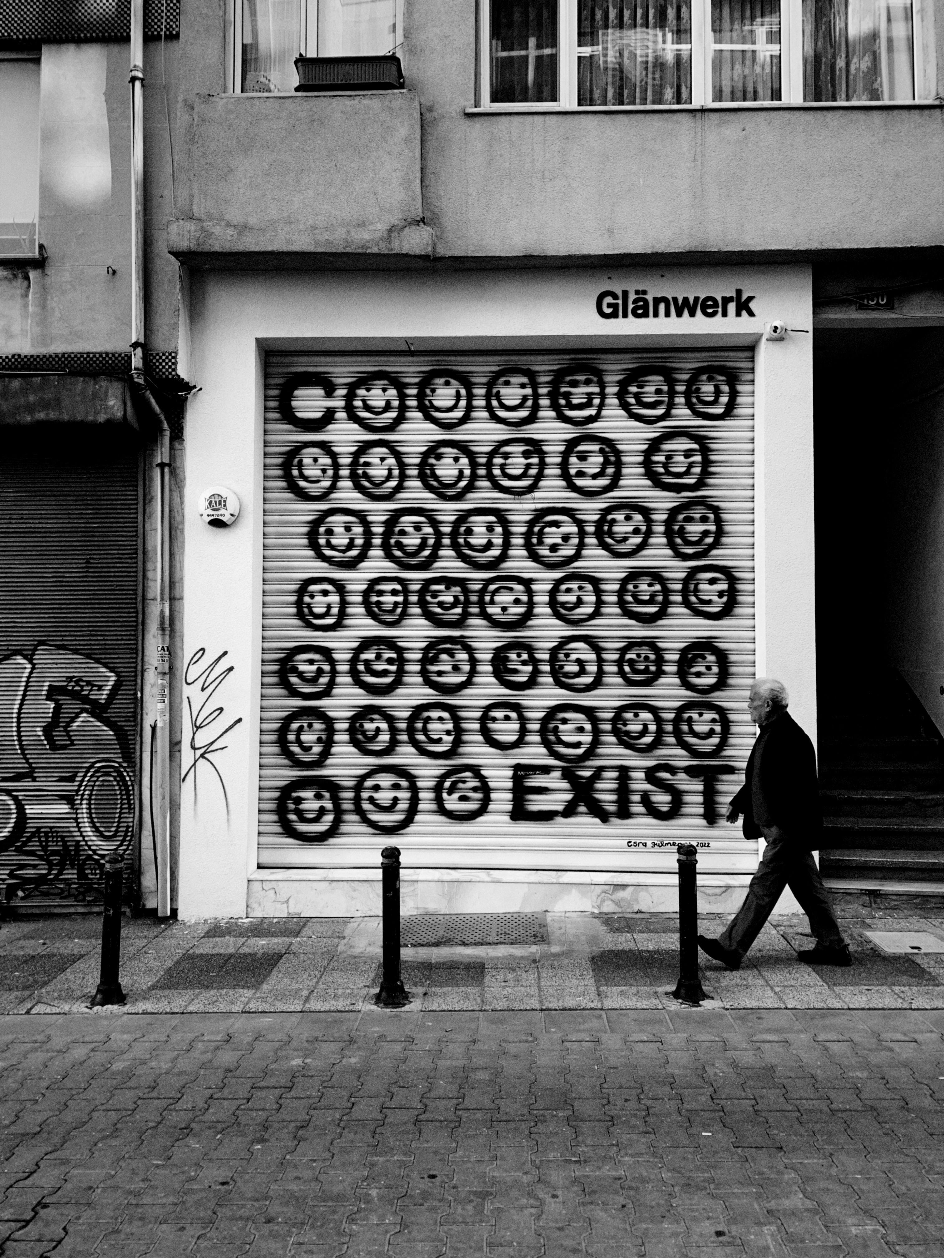 Elderly man walking past graffiti-covered wall in İstanbul street.