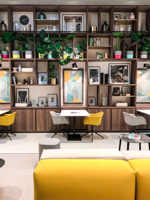 Free Stylish indoor lounge with wooden shelves, art, and vibrant seating. Stock Photo