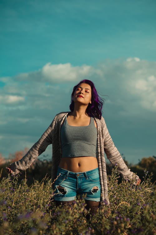 Woman in Crop Top and Short  Standing on Green Grass Field 
