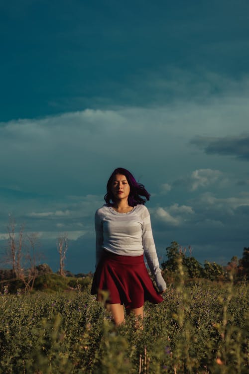 Woman in Gray Long-sleeved Shirt and Maroon Skirt Standing on Plant  Field