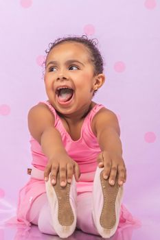Smiling child in pink dress posing playfully in studio setting.