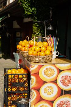 Wicker baskets filled with bright oranges on a street vendor's stand under sunlight.