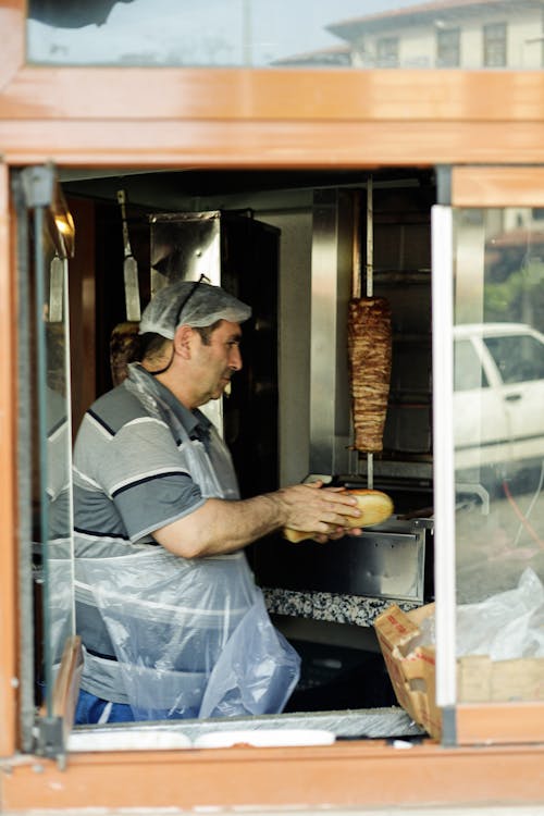 A man is cooking food in a window