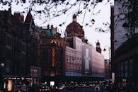 伦敦繁忙的城市交通中，矗立着历史悠久的哈罗德建筑，映衬着黄昏景色