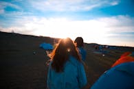 日落时分，露营场景宁静祥和，帐篷旁的人们正享受着户外活动