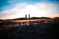 两位朋友站在岩石景观中，迎着绚烂的日落，拥抱自然与友谊