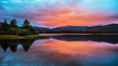 宁静的日落倒映在布雷肯里奇湖上，与生动的天空和山峦交相辉映
