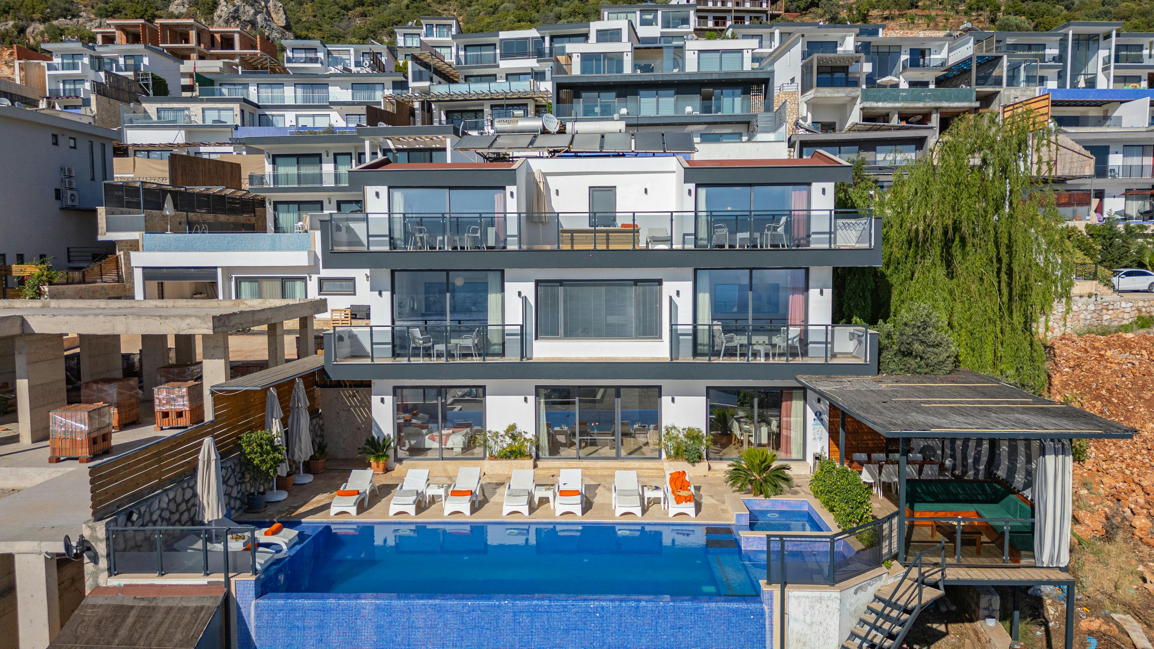 Modern luxury villa with infinity pool on a hillside, featuring stunning architectural design.