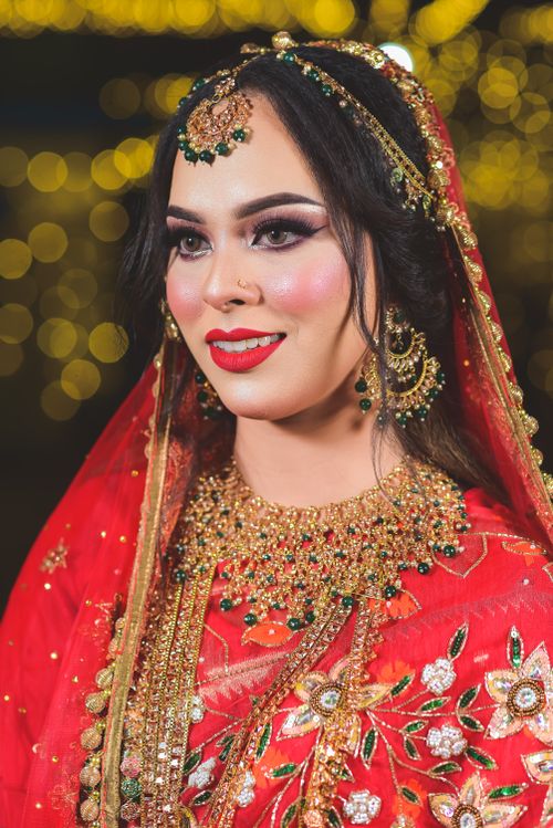 Free Beautiful South Asian bride adorned with intricate jewelry and a vibrant red sari, captured in a festive setting. Stock Photo