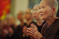 在寺庙内，一位虔诚的佛教女修行者被同修们包围着祈祷