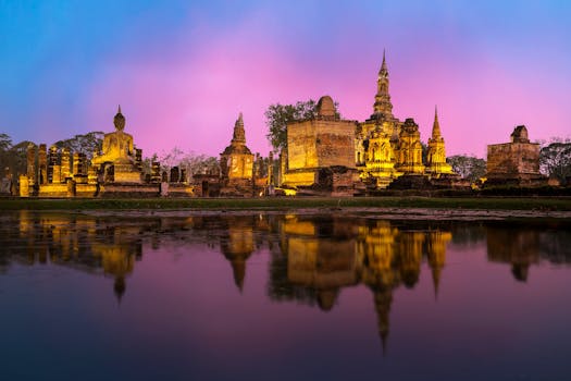 Beautiful sunset view of Wat Mahathat temple in Sukhothai, Thailand, reflecting in the surrounding water.
