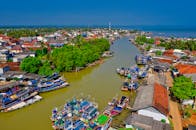 一个生动的空中镜头捕捉了停靠在阳光明媚的沿海城镇繁华港口的五颜六色的渔船