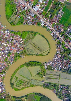 从令人叹为观止的鸟瞰图中，可以看到一条河流蜿蜒穿过充满活力的印尼小镇和郁郁葱葱的风景