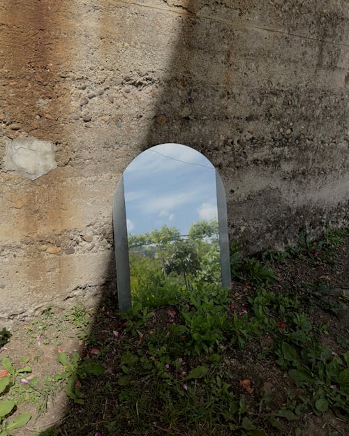 A mirror is sitting in the middle of a concrete wall