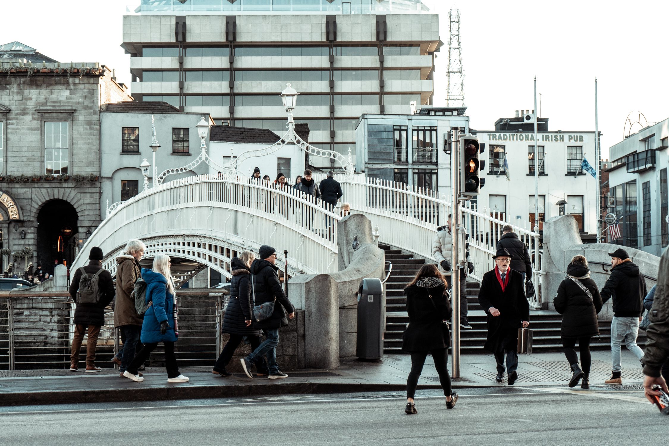People crossing the iconic Ha'penny Bridge in Dublin, Ireland, during a typical day
