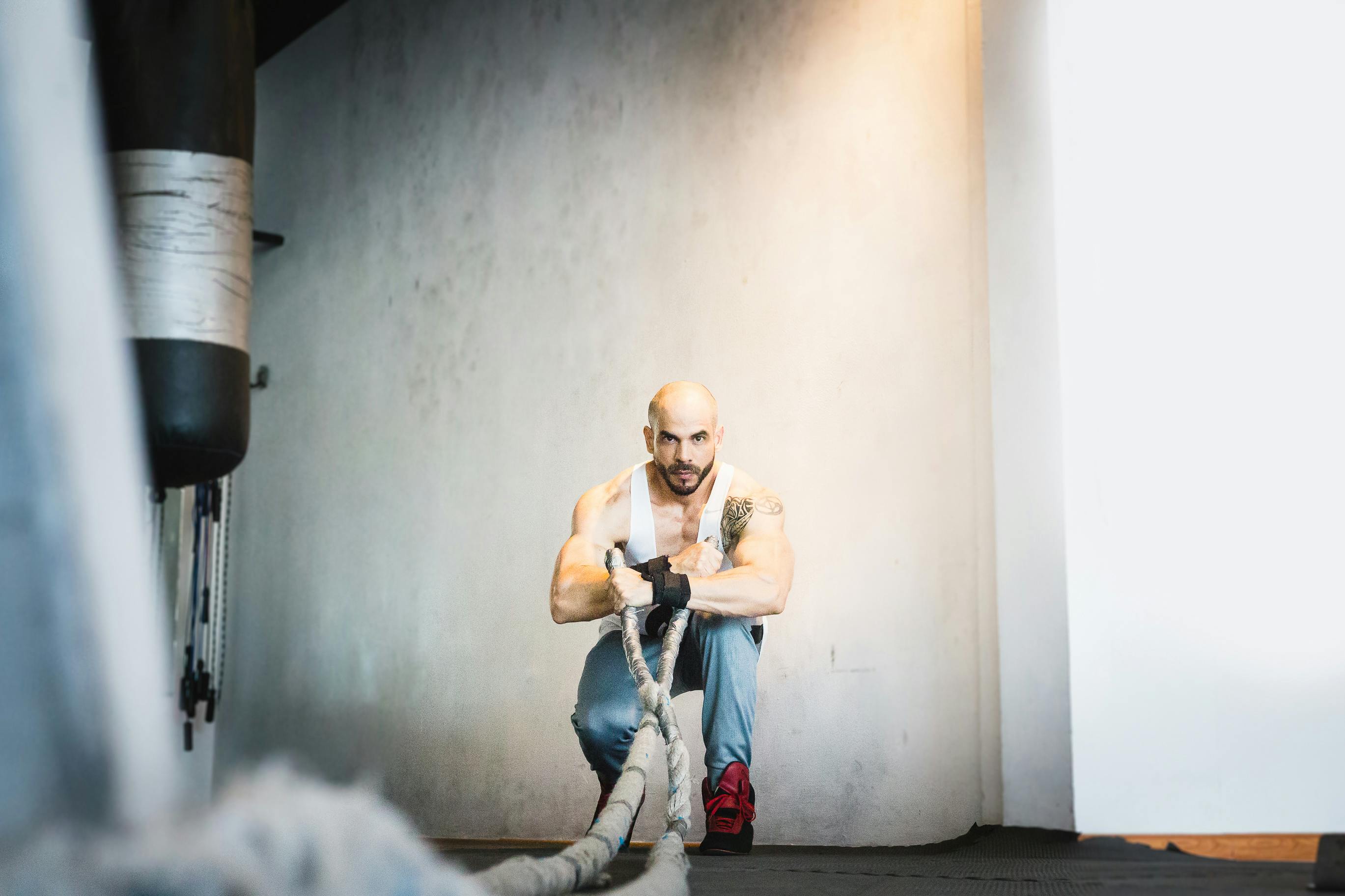 Strong muscular man exercising with battle ropes in a gym setting, showcasing strength and determination.