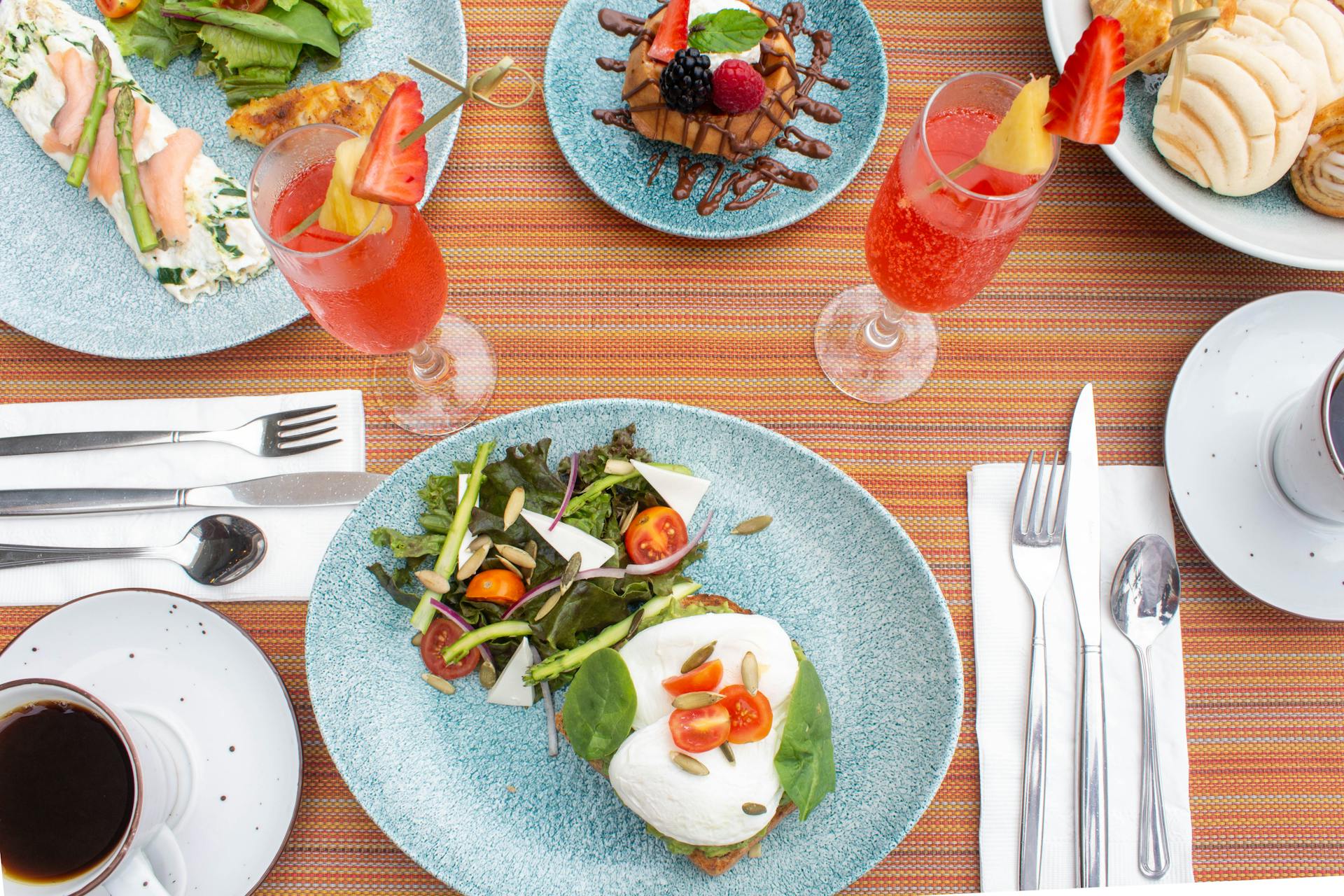 A vibrant breakfast table setting in Puerto Vallarta with fresh salad, pastries, and drinks.