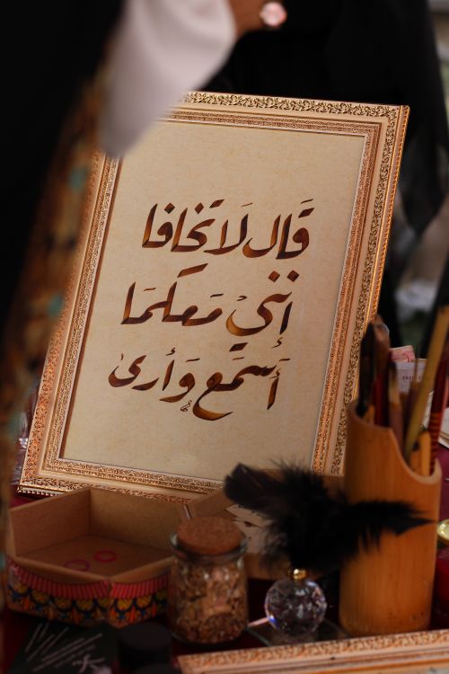 Free Close-up of Arabic calligraphy in a decorative frame with writing tools. Stock Photo