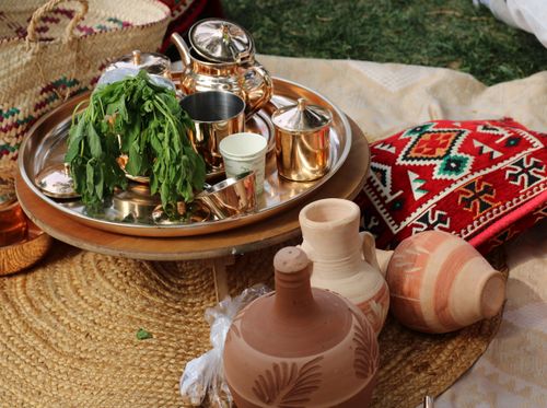 Free A rustic outdoor picnic scene featuring pottery, herbal tea, and colorful textiles. Stock Photo