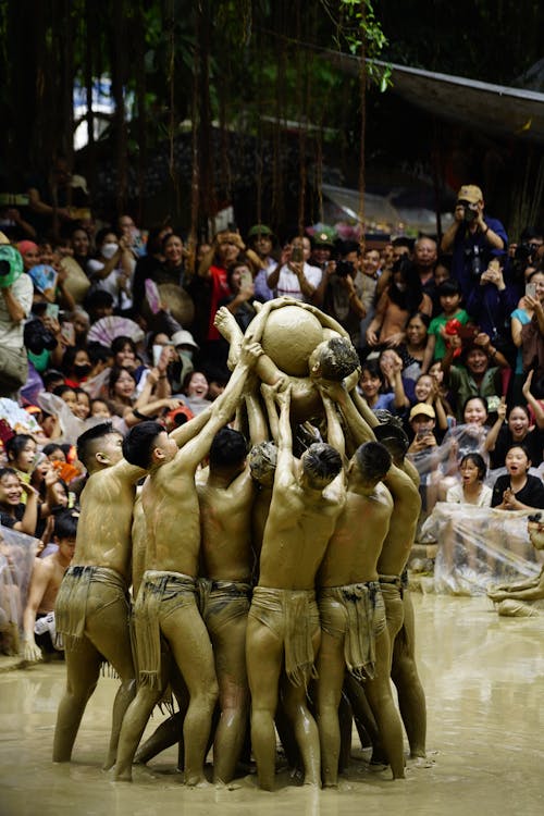 A group of people are holding a ball in the mud