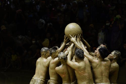 A group of people holding a ball in the mud