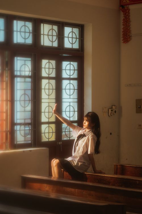 Free Asian woman in school uniform sitting in a sunlit classroom window, daytime in Vietnam. Stock Photo
