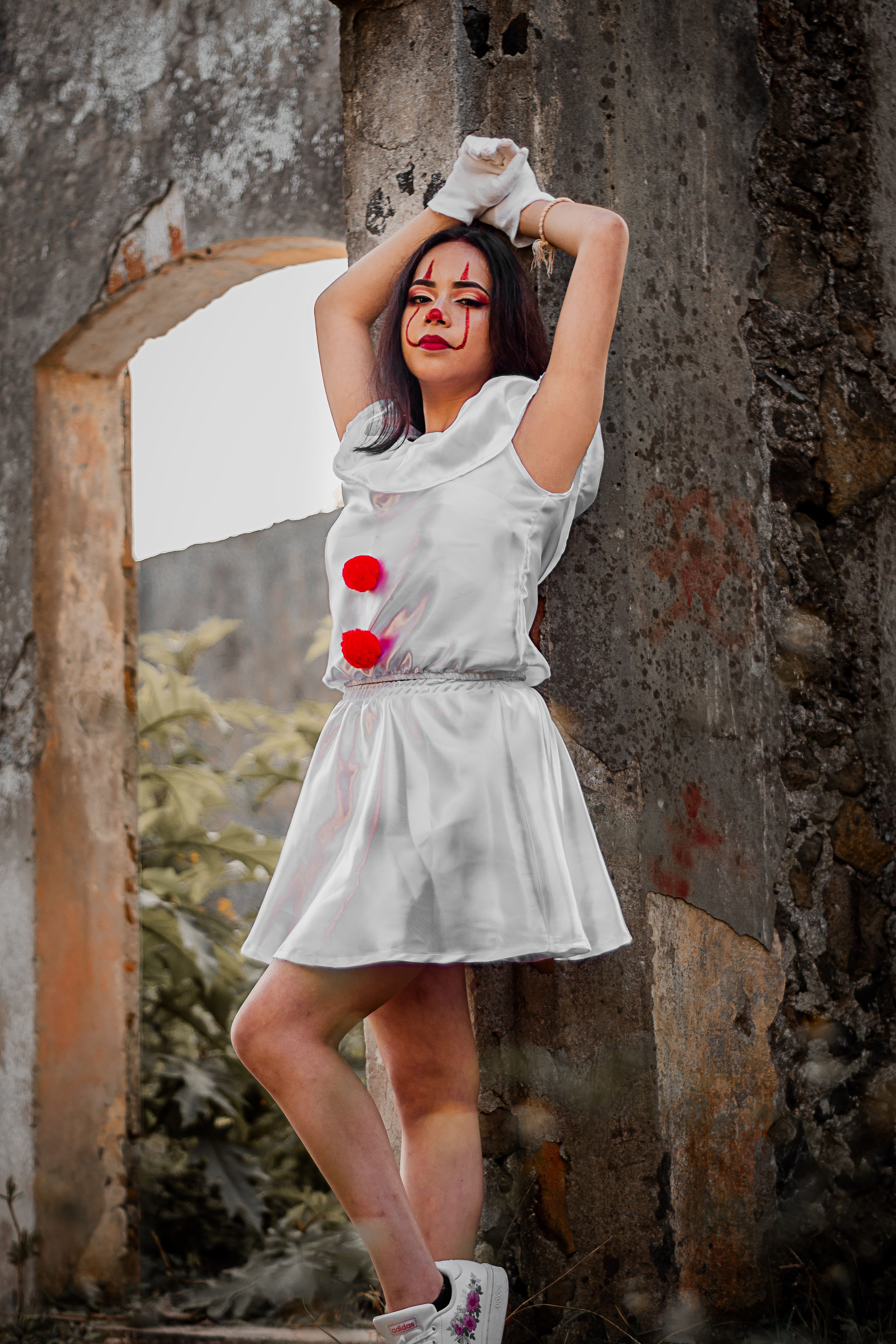 A woman in a clown costume poses creatively at historic ruins in Mexico.