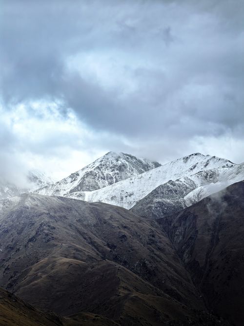 Free Breathtaking view of snow-capped mountains in Almaty, Kazakhstan under a dramatic cloudy sky. Stock Photo