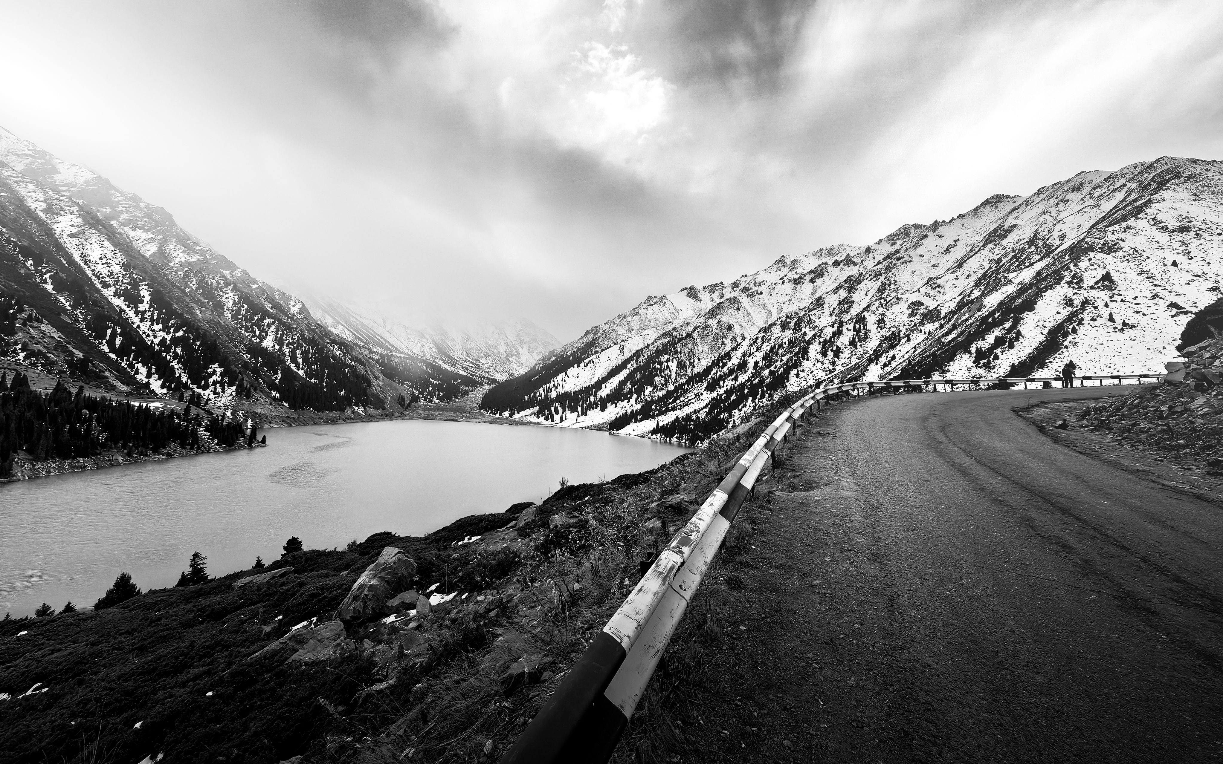 Snow-covered mountain road with a lakeside view in Almaty region, Kazakhstan.