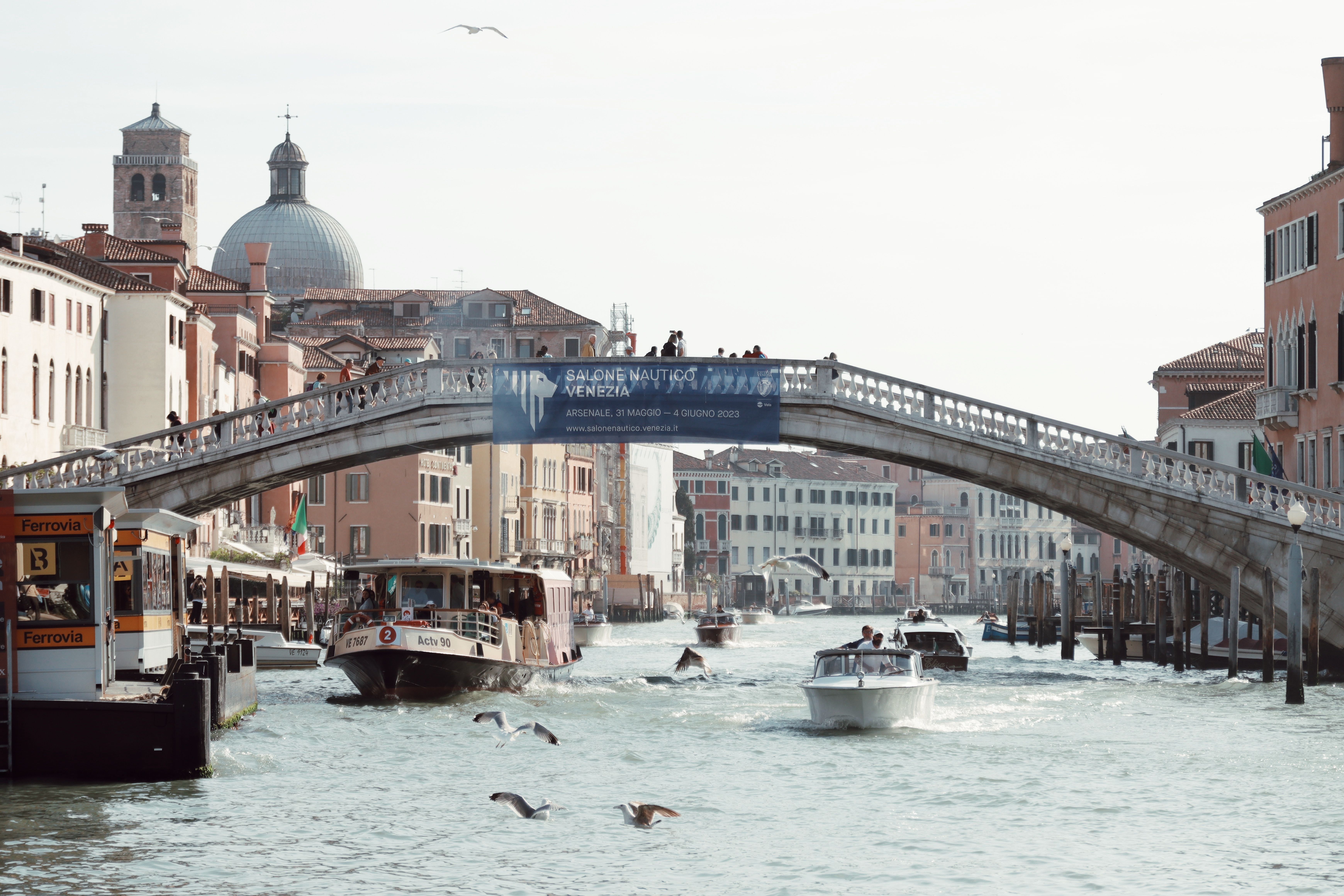 Scenic view of boats navigating a Venetian canal under a classic stone bridge, Venice, Italy.
