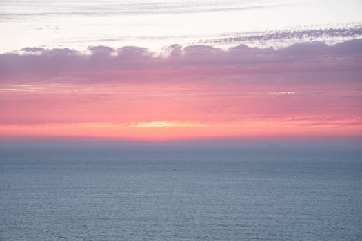摩洛哥丹吉尔的海面上，日落充满活力，泛着粉红与紫色的色调